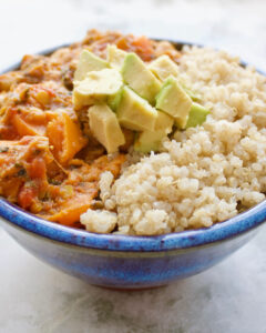 A bowl of sweet potato curry with quinoa and avocado pieces